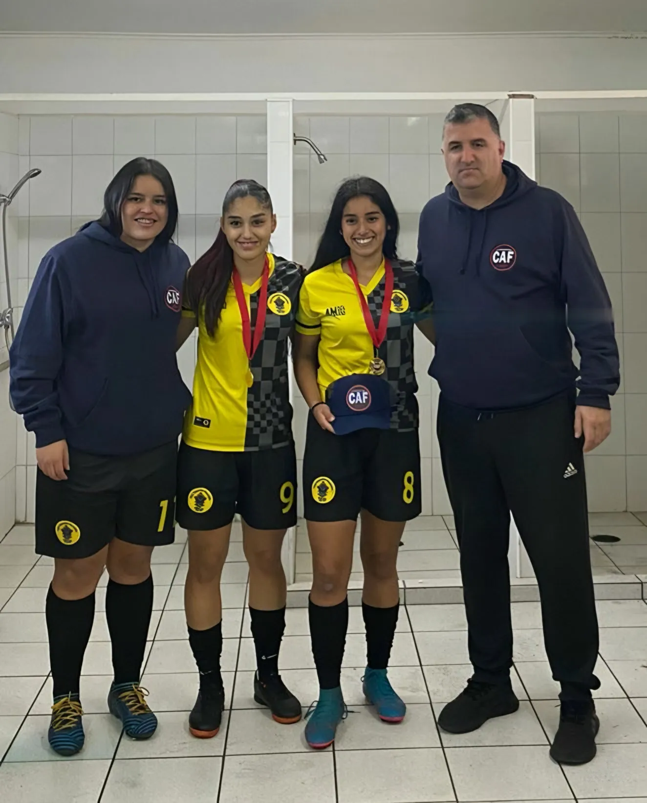 Tres jugadoras de fútbol 7 con sus medallas junto a un representante de la fundación.