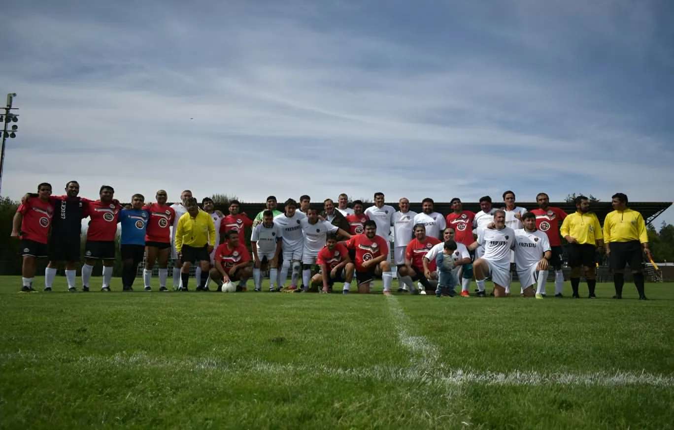 Plano general de dos equipos de fútbol y árbitros formados en una cancha de pasto.